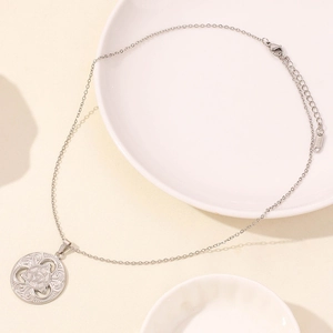 Macro di una collana con ciondolo triquetra d'argento con catena a O su un piatto