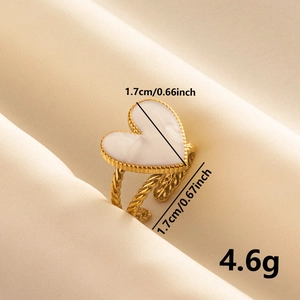 Détail macro d'une bague cœur vintage dorée avec émail blanc et anneau torsadé