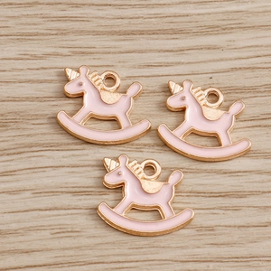 Trois pendentifs cheval à bascule licorne en émail rose avec bordure dorée sur bois