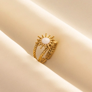 Macro shot of gold sunburst ring with white inlay and twisted double-strand band