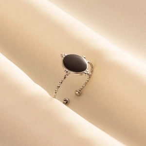Détail d'une bague en acier 304 avec pierre ovale noire sur satin beige chic