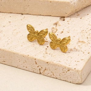 Makro-Detail goldener Schmetterlings-Ohrstecker mit strukturierter Flügeloberfläche