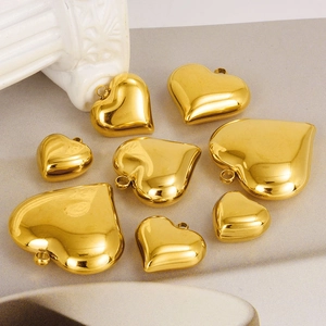 Gepolijste gouden hartjes hangers in drie maten op grijze steen met klassiek decor