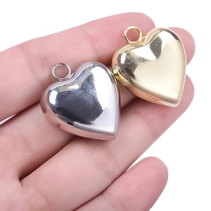 Detailweergave van kleine goud en zilver hart hangers vastgehouden op de vingers
