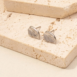 Detailansicht der blattförmigen Edelstahl-Ohrstecker auf einer Natursteinoberfläche