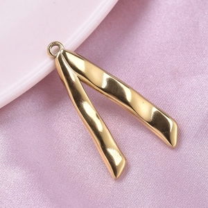 Macro shot of gold V-shaped irregular twisted metal pendant on pink velvet background
