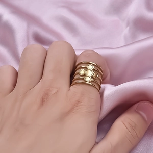 Five-layer gold stainless steel open ring with metal floral accents on pink silk fabric