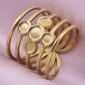 Detailed macro view of 304 stainless steel multi-layer gold ring on soft pink silk fabric