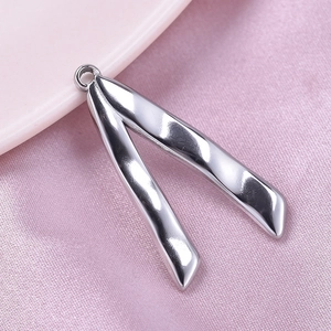 Macro shot of polished silver V-shaped stainless steel pendant on pink satin fabric