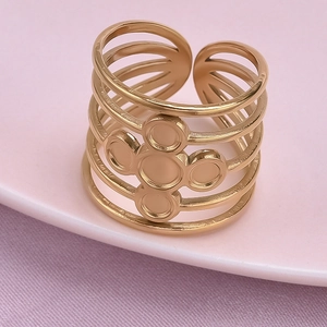 Detailed close-up of a multi-layer golden stainless steel ring with flower charm on pink tray