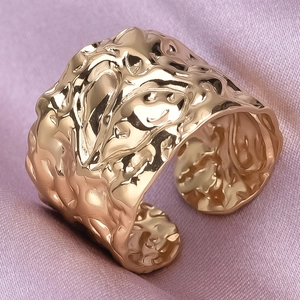 Macro detail of gold irregular hammered texture ring on elegant pink silk background