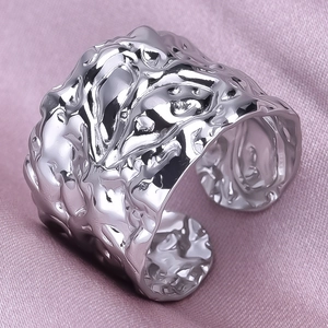 Macro shot of silver irregular lava texture wide band ring on soft silk background