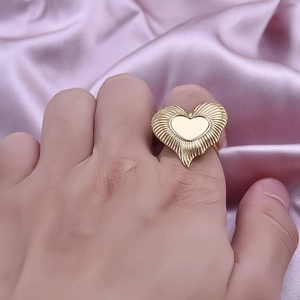 Irregular 18K gold heart ring with sunburst texture on pink satin background