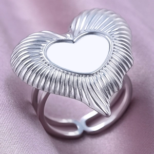 Macro detail of silver irregular heart ring with radial texture on purple satin background