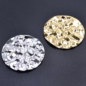 Macro detail of textured gold and silver round hammer pattern pendants in 304 stainless steel