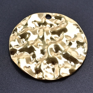 Macro shot of gold hammered round pendant texture and polished stainless steel finish