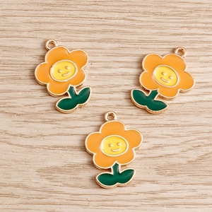 Dettaglio di tre ciondoli a forma di fiore in smalto colorato con volti sorridenti