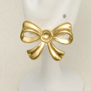 Polished golden stainless steel bow stud earrings displayed on a white jewelry stand