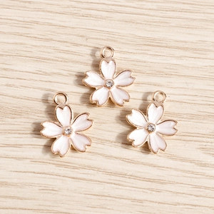Close-up of pink cherry blossom enamel pendants with small central rhinestone and gold alloy