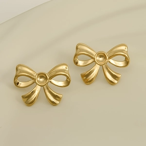 Close-up of golden bow earrings featuring a matte metal texture and vintage design