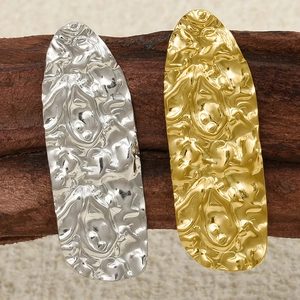 Macro shot of gold and silver irregular liquid metal texture earrings on dark wood