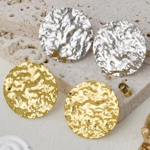 Macro detail of oval hammered gold and silver earrings on a natural stone display