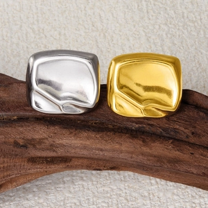 Macro shot of gold and silver square rings with irregular texture on dark wood base