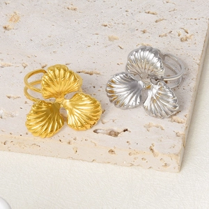 Macro detail of gold and silver shell-textured rings on a minimalist stone tray