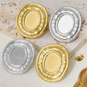 Detailed macro view of vintage gold and silver oval hammered metal earrings on stone