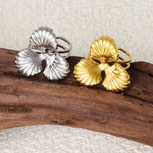 Detail of 304 stainless steel rings with gold and silver shell petals on wood