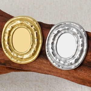 Close-up of gold and silver oval stud earrings with liquid metal edges on wood texture