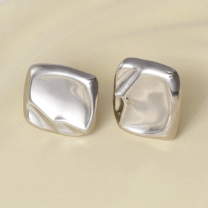 Macro detail of irregular silver earrings featuring liquid metal texture and matte finish