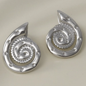 Vista macro degli orecchini a conchiglia in argento con spirale geometrica e puntini