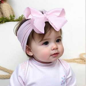 Detail of soft light pink nylon baby headband with a large ribbed bow and frayed edges