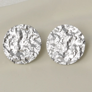 Detailed macro view of retro oval earrings featuring a hammered silver metal texture