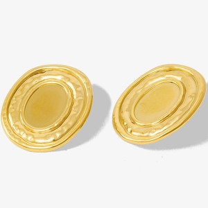 Close-up of vintage oval gold earrings with matte finish and textured wavy edges
