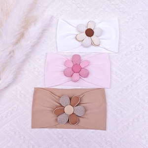 Détail de trois bandeaux pour bébé en tricot côtelé avec des fleurs en tissu fait main
