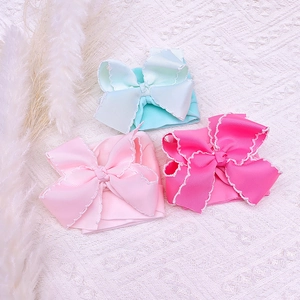 Close-up of baby nylon headbands with large ribbed bows and delicate white scalloped edges