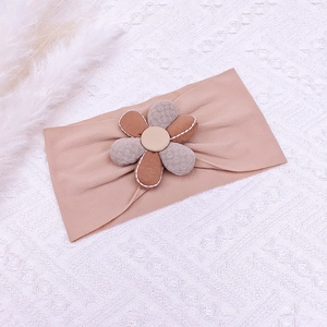 Vue détaillée d'une fleur en tissu à 6 pétales sur un bandeau élastique pour nouveau-né