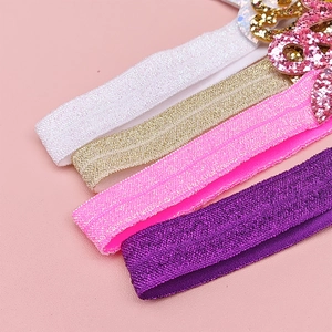 Détail de quatre bandeaux pailletés pour bébé en blanc, doré, rose et violet