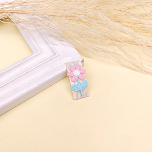 Details einer bestickten rosa Blume mit hellblauen Blättern auf dem Ripsband-Haarclip