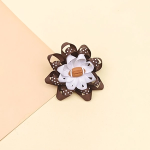Détail d'une barrette à pois marron avec un petit accessoire en forme de ballon de football