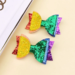 Dettaglio ravvicinato delle mollette glitterate arcobaleno con texture di tessuto luccicante