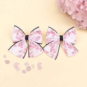 Détail de pinces à cheveux avec nœuds à imprimé floral rose et bordure noire élégante