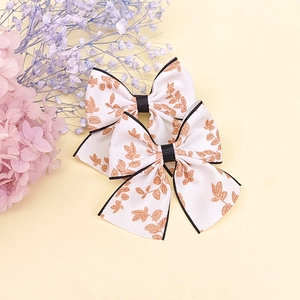 Détail de pinces à cheveux à nœud floral avec motif de feuilles d'or et ruban