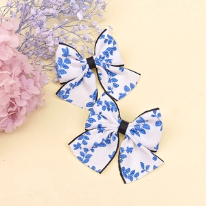 Détail de deux barrettes noeuds faites main avec motif de feuilles bleues et bord noir