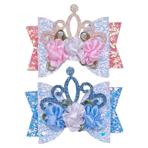 Close-up of pink and blue glitter crown hair clips with satin flower details