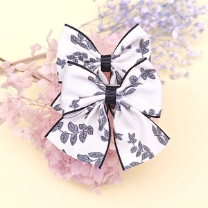 Détail de pinces à cheveux en tissu avec imprimé feuilles et ruban central