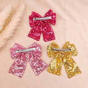 Close-up of sequin bow hair clips in rose, pink, and gold with metal alligator grips
