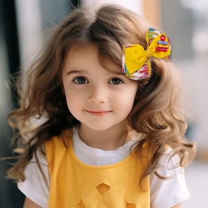 Détail d'une pince à cheveux avec nœud, motifs crayons et petits livres sur une fille